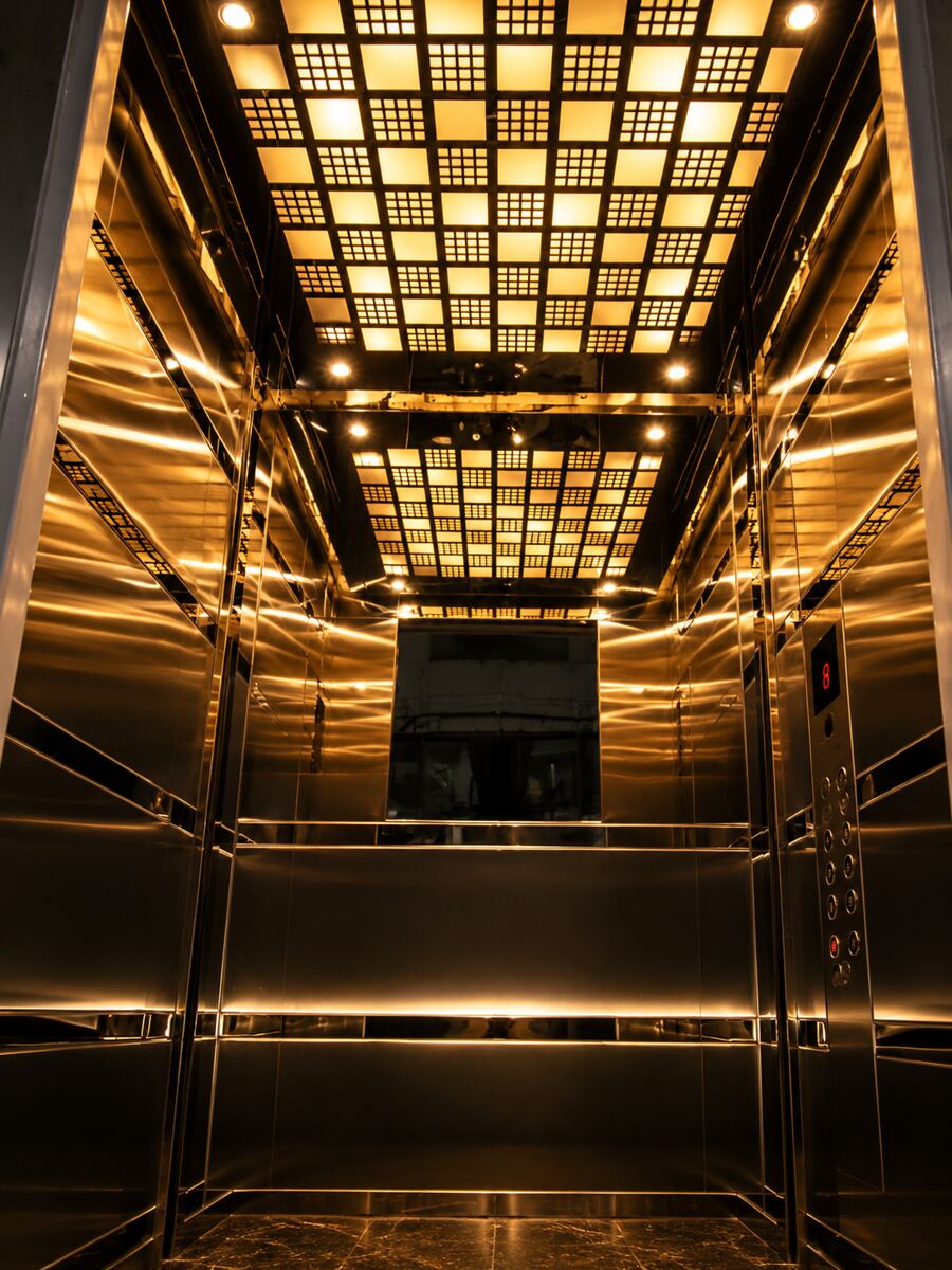 Elevator cabin with illuminated golden ceiling grid
