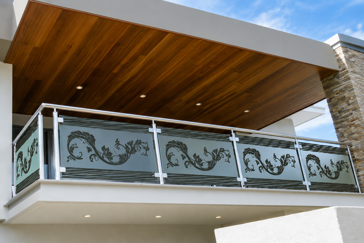 Balcony with steel and glass railing beneath a wood-clad ceiling
